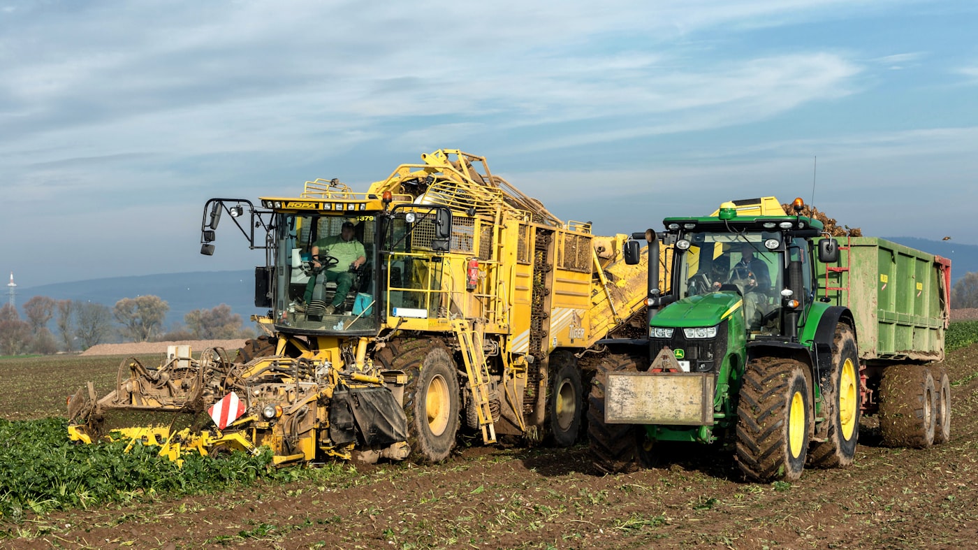 Erntemaschine und Traktor mit Anhänger bei der Feldarbeit
